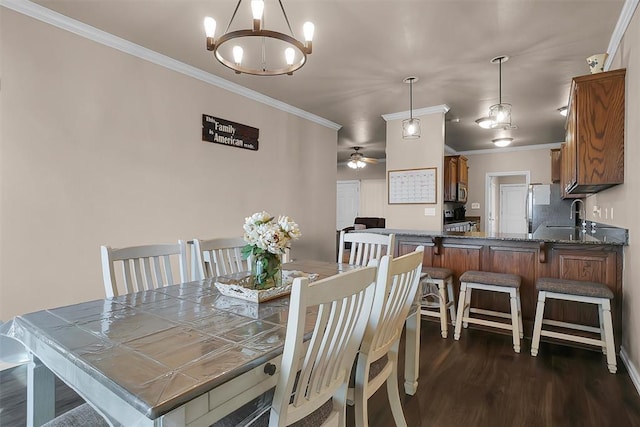 dining room with crown molding, sink, dark hardwood / wood-style floors, and ceiling fan with notable chandelier