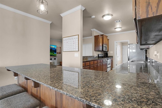 kitchen with stainless steel appliances, a kitchen breakfast bar, kitchen peninsula, and sink