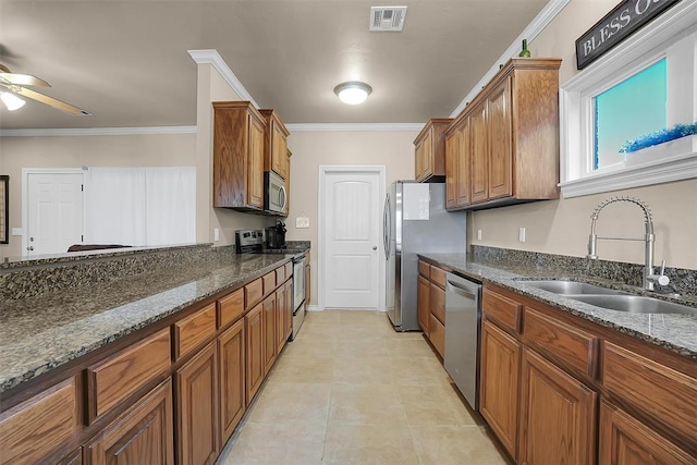 kitchen with stainless steel appliances, ornamental molding, sink, and dark stone countertops