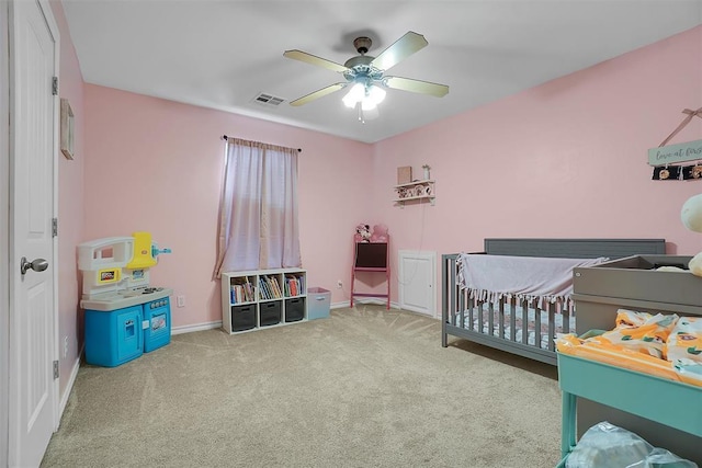 carpeted bedroom featuring a nursery area and ceiling fan