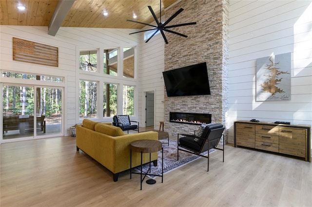 living room featuring a stone fireplace, wood ceiling, high vaulted ceiling, light hardwood / wood-style flooring, and beamed ceiling