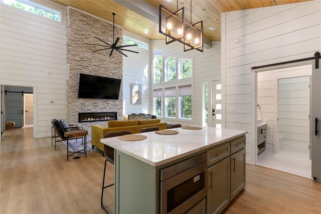 kitchen with stainless steel microwave, decorative light fixtures, a barn door, and a kitchen island