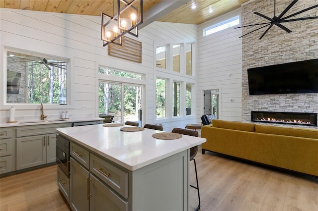 kitchen with a kitchen island, pendant lighting, high vaulted ceiling, wooden walls, and sink