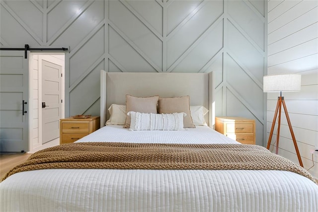 bedroom featuring hardwood / wood-style flooring and a barn door