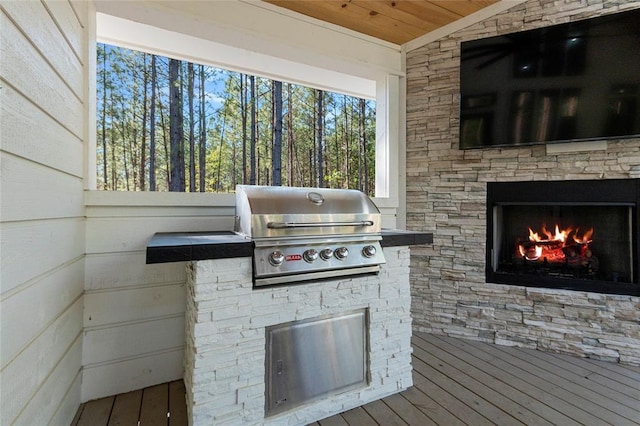 view of patio with a wooden deck, grilling area, an outdoor stone fireplace, and an outdoor kitchen