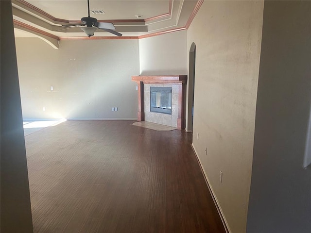 unfurnished living room with a tile fireplace, crown molding, dark hardwood / wood-style floors, and ceiling fan