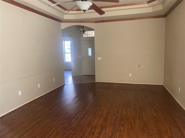 unfurnished room with a raised ceiling, crown molding, dark wood-type flooring, and ceiling fan