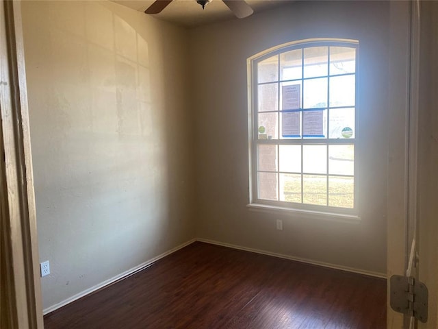 empty room with plenty of natural light, dark hardwood / wood-style floors, and ceiling fan