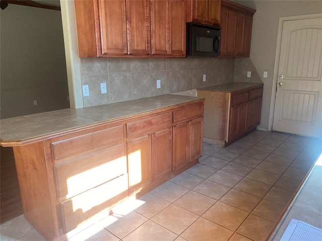 kitchen featuring decorative backsplash, kitchen peninsula, and light tile patterned flooring