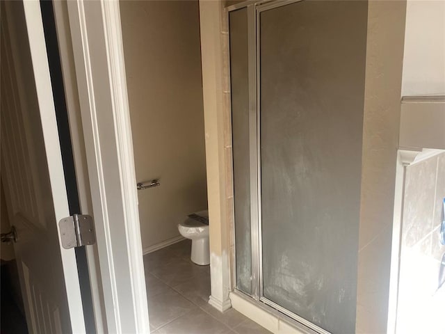 bathroom with tile patterned floors, toilet, and an enclosed shower