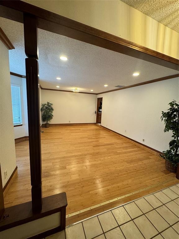 interior space with crown molding, light tile patterned flooring, and a textured ceiling