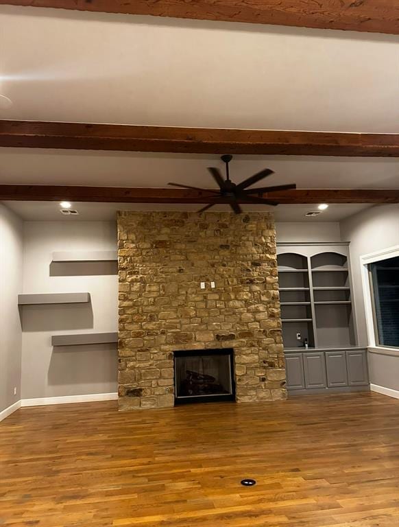 unfurnished living room featuring hardwood / wood-style flooring, a stone fireplace, and ceiling fan