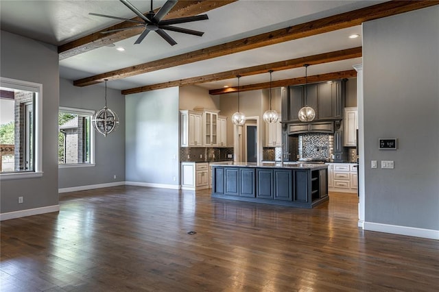 kitchen with pendant lighting, decorative backsplash, an island with sink, and beamed ceiling