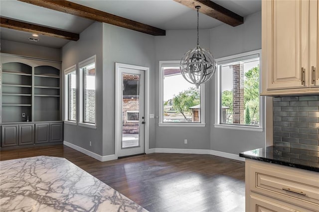 interior space featuring dark wood-type flooring, beam ceiling, an inviting chandelier, and a wealth of natural light