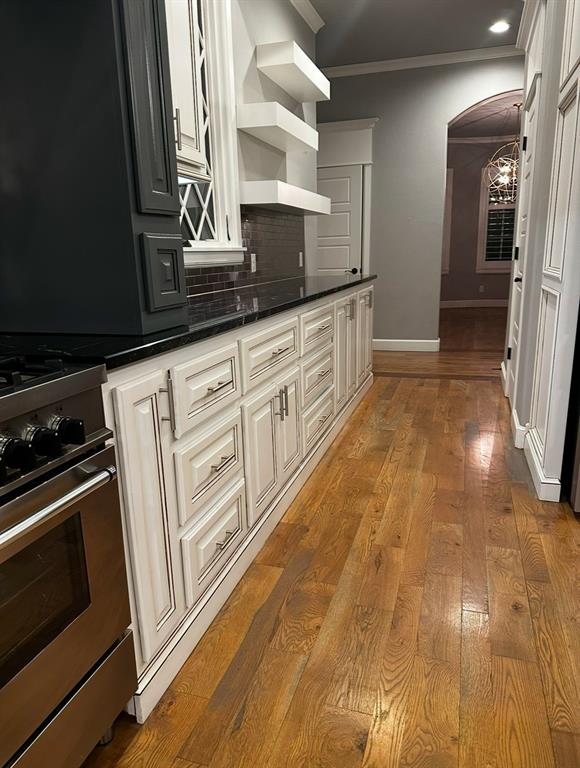 kitchen with backsplash, ornamental molding, light hardwood / wood-style floors, high end stove, and wall chimney range hood