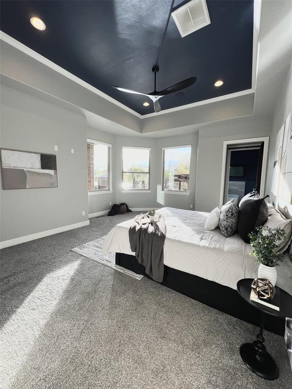 carpeted bedroom with crown molding, a tray ceiling, and ceiling fan