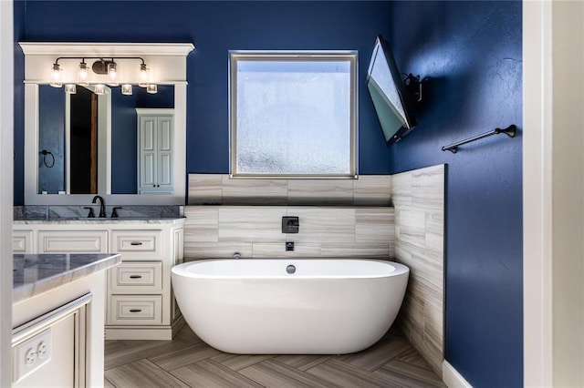 bathroom with a tub to relax in, parquet flooring, vanity, and tile walls