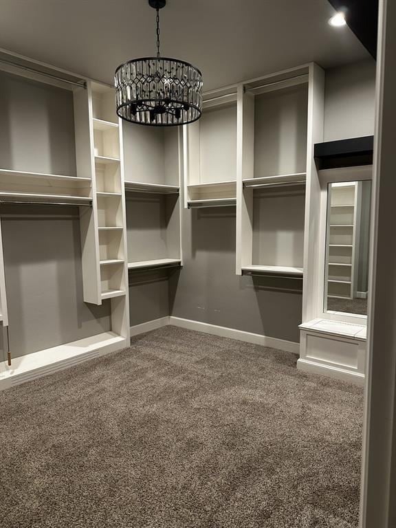 walk in closet featuring a chandelier and carpet flooring