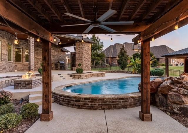 pool at dusk with a grill, a patio, ceiling fan, and an outdoor fire pit