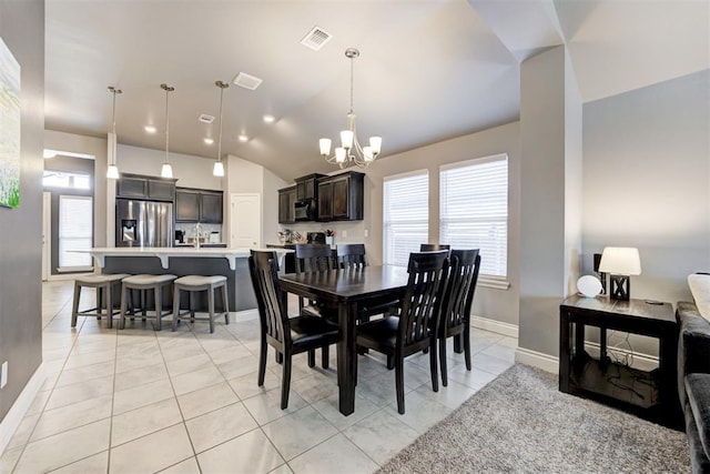 dining room featuring sink, a chandelier, vaulted ceiling, and light tile patterned floors