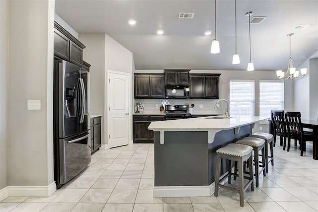 kitchen with sink, hanging light fixtures, a center island with sink, a kitchen breakfast bar, and black appliances