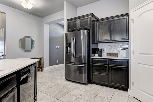 kitchen with tasteful backsplash, stainless steel refrigerator with ice dispenser, black dishwasher, and light tile patterned floors