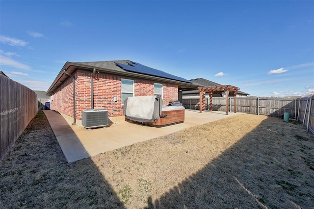 back of property featuring central AC, a patio area, solar panels, a hot tub, and a pergola