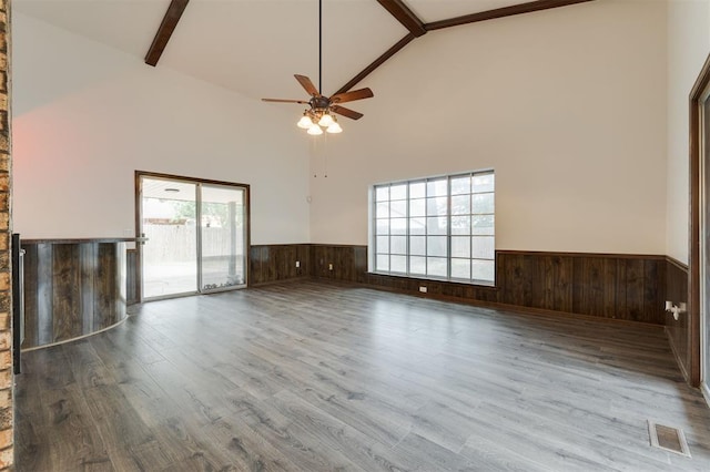 unfurnished living room with hardwood / wood-style floors, beam ceiling, a wealth of natural light, and high vaulted ceiling