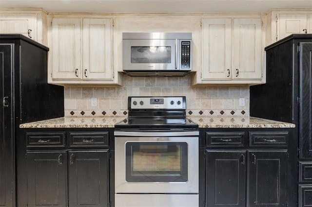 kitchen with light stone countertops, stainless steel appliances, and cream cabinetry