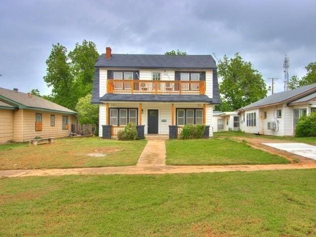 view of front of property featuring a balcony and a front lawn