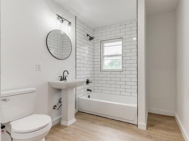 bathroom featuring hardwood / wood-style floors, tiled shower / bath, and toilet