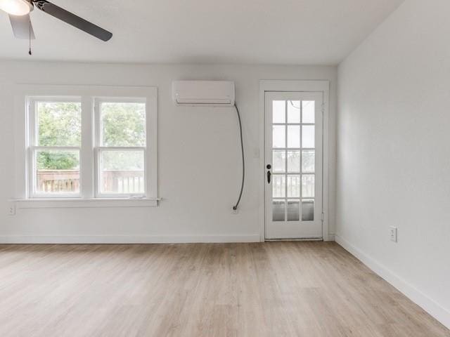 unfurnished room featuring ceiling fan, a wall unit AC, and light hardwood / wood-style flooring