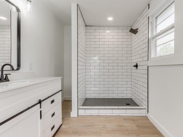 bathroom featuring vanity, wood-type flooring, and a tile shower