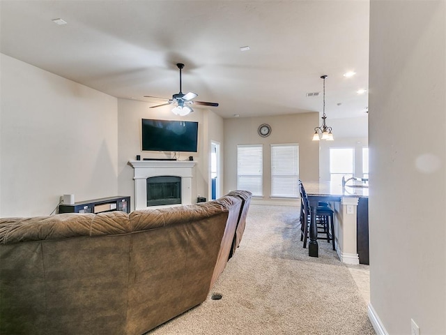 living room featuring ceiling fan with notable chandelier and light carpet