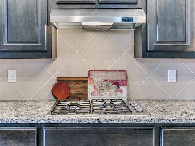 kitchen with backsplash, light stone countertops, exhaust hood, and stainless steel gas stovetop