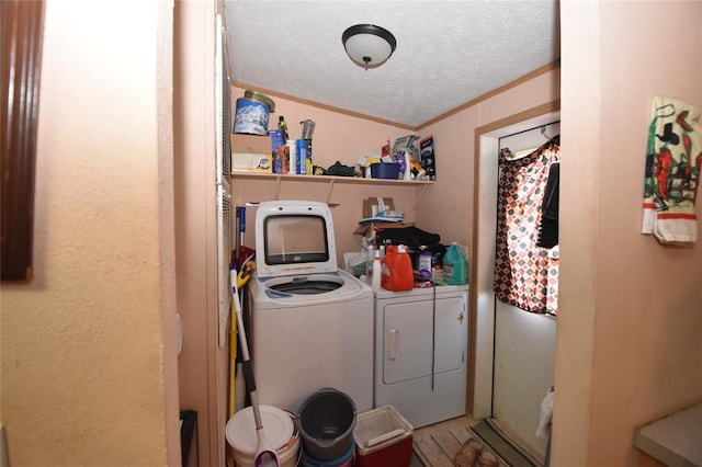 clothes washing area featuring crown molding, separate washer and dryer, and a textured ceiling