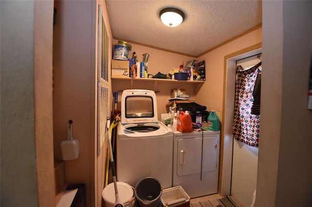 laundry area featuring ornamental molding, washer and dryer, and a textured ceiling