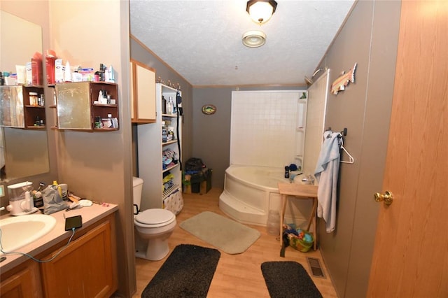 bathroom featuring wood-type flooring, vanity, a washtub, toilet, and a textured ceiling