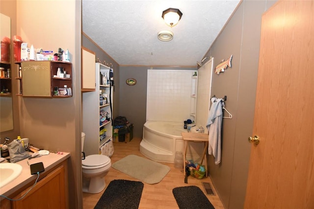 bathroom with toilet, a textured ceiling, vanity, a tub, and hardwood / wood-style floors