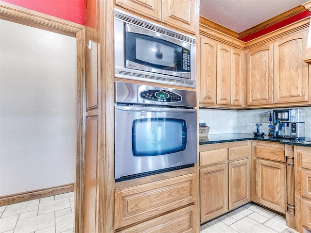 kitchen featuring stainless steel appliances, tasteful backsplash, dark stone countertops, and light tile patterned floors