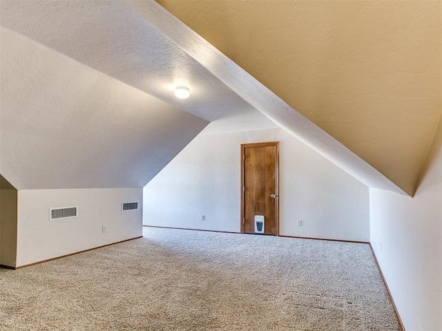 bonus room featuring vaulted ceiling, carpet floors, and a textured ceiling