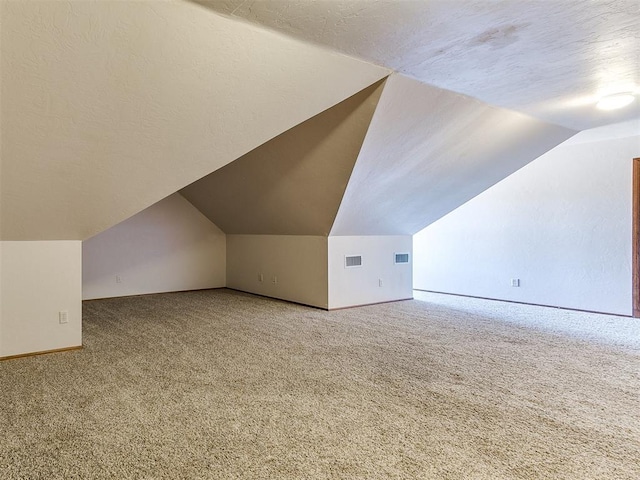 additional living space featuring lofted ceiling, a textured ceiling, and carpet flooring