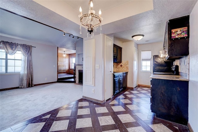 kitchen with an inviting chandelier, a textured ceiling, dark brown cabinetry, and a healthy amount of sunlight