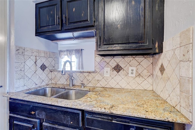 kitchen featuring light stone counters, dishwasher, sink, and backsplash