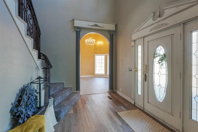 entryway with a towering ceiling, wood-type flooring, and plenty of natural light