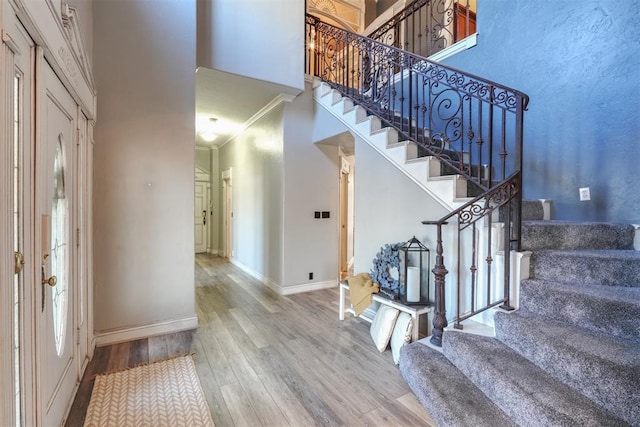 entryway featuring ornamental molding, hardwood / wood-style floors, and a high ceiling