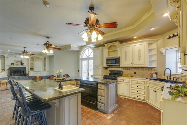 kitchen featuring a kitchen bar, sink, a center island with sink, black range with electric cooktop, and backsplash