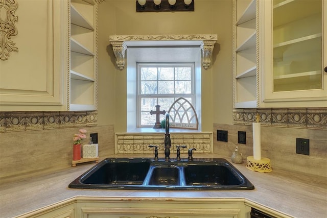 kitchen with tasteful backsplash, sink, cream cabinets, and black dishwasher