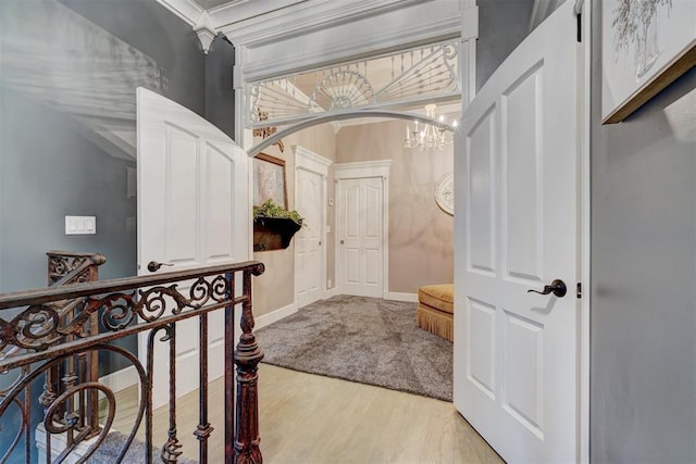 corridor featuring crown molding, a notable chandelier, and light wood-type flooring