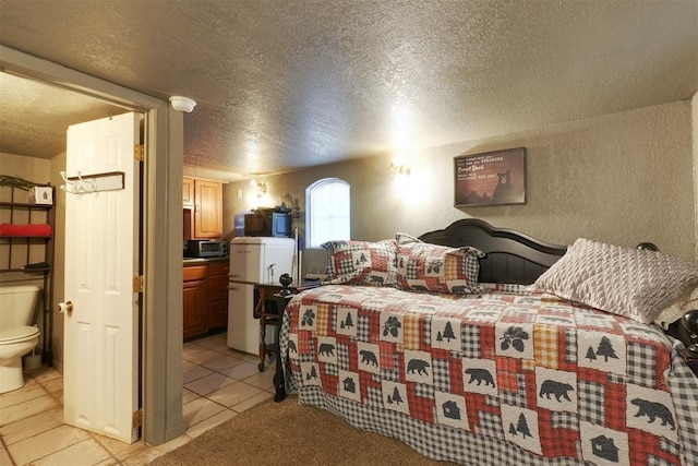 tiled bedroom featuring fridge, connected bathroom, and a textured ceiling